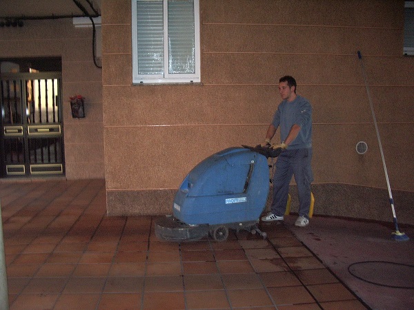 Operario de Galiport limpiando un soportal con fregadora industrial